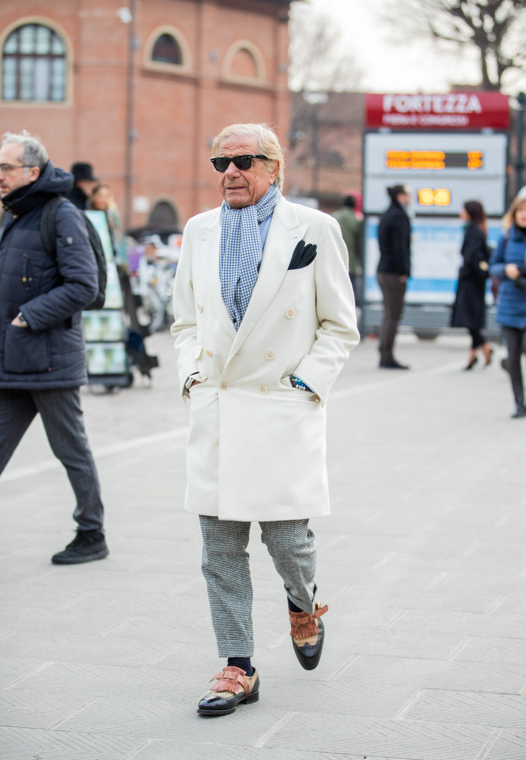 L’idole des ploucs: le manteau blanc, la pochette assortie aux lunettes de soleil. Au moins, l’écharpe façon cochonou-vichy nous évite la vue d’une cravate brodée d’un 7.