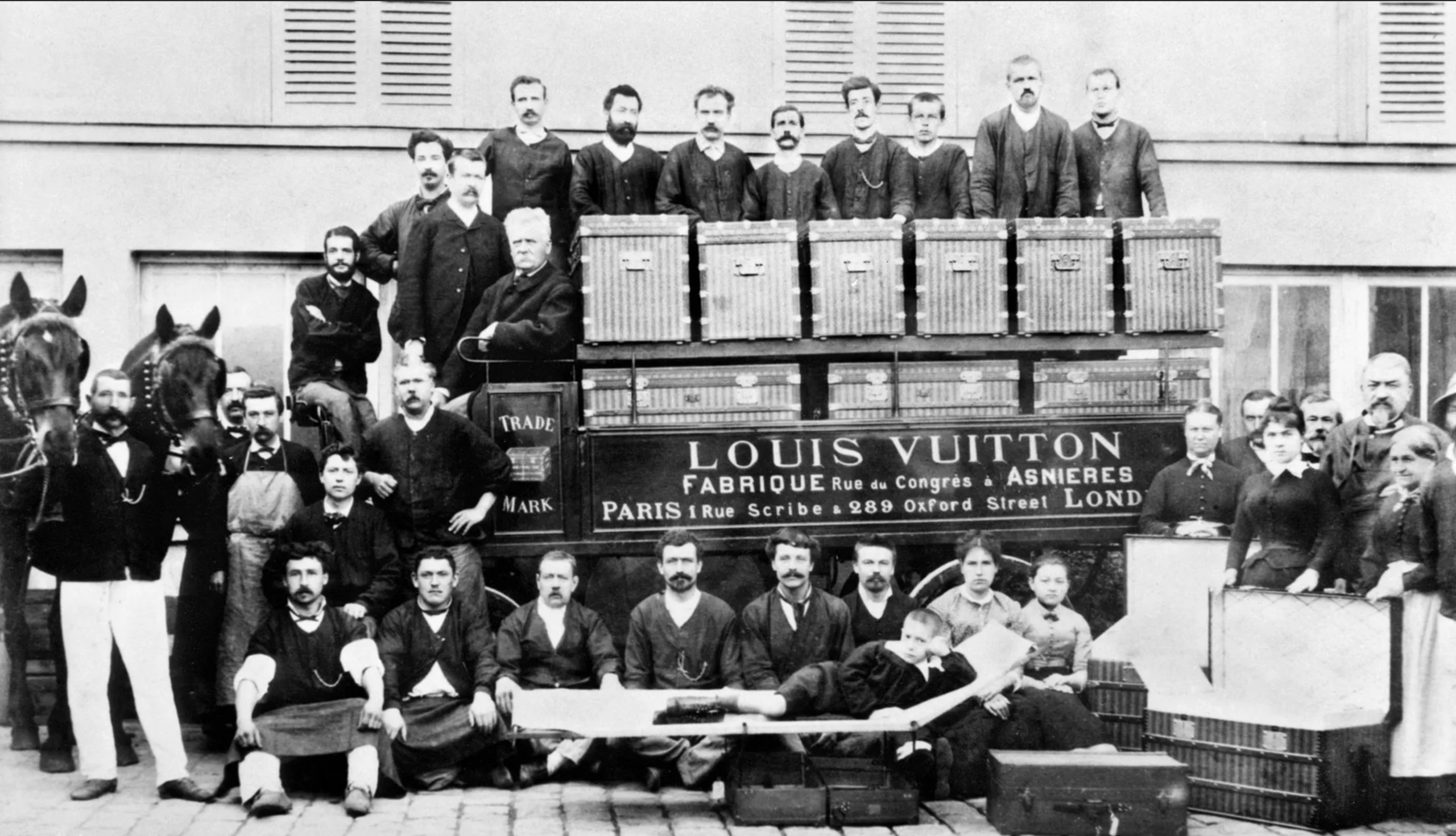 Les atelier d'Asnières de Louis Vuitton vers 1888. Louis Vuitton est assis à la place du conducteur. Son petit-fils est allongé sur la malle lit du premier plan. En dehors de l’activité résiduelle de malletier qu’a la marque aujourd’hui, il est évident que le lien entre l’entreprise à ses débuts et ce qu’elle est aujourd’hui est ténu. (Source : Louis Vuitton)